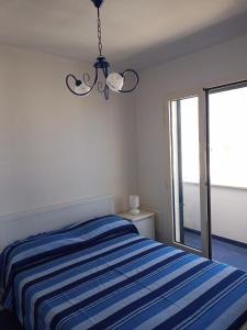 a bedroom with a blue and white striped bed and a window at Casa Vacanza in Torre San Giovanni Ugento