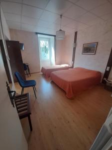 a bedroom with two beds and a blue chair at Relais du Bois du Four in Saint-Léons