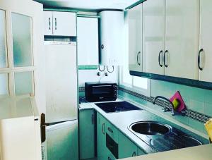 una cocina con armarios verdes y blancos y fregadero en IPANEMA PLAYA 2 Habitaciones, en Almuñécar