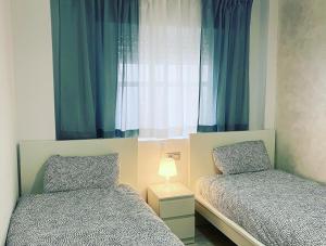 sypialnia z 2 łóżkami i oknem z niebieskimi zasłonami w obiekcie BALCON PLAYA Y PISCINA 2 Habitaciones IPANEMA PONDOS w Almuñécar +6 zdjęć
