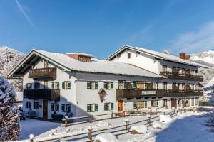 ein großes weißes Gebäude mit Schnee auf dem Boden in der Unterkunft Hotel Binderhäusl in Berchtesgaden