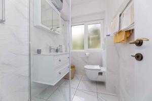 a white bathroom with a toilet and a sink at Apartment in Vrbnik/Insel Krk 36871 in Vrbnik