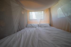 a white bed in a room with a window at Lodge Holidays - Camping Podere Sei Poorte in Genga