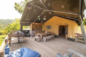 a tent with a wooden deck with a table and benches at Lodge Holidays - Camping Podere Sei Poorte in Genga +47 photos