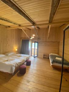 2 letti in una camera con pareti in legno e pavimenti in parquet di Hotel Chubezeni a Mestia