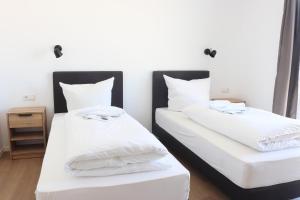two beds in a room with white sheets and pillows at Motel Bergtheim - Self Check-in in Bergtheim
