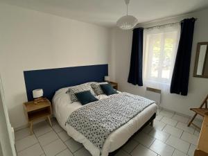 una camera da letto con un letto con testiera blu e una finestra di bel appartement 2 chambres au coeur du village a Eyragues