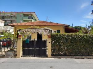una casa con una puerta negra y un seto en Villa la Casetta con giardino a 30 m dal mare, en San Bartolomeo al Mare
