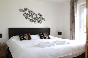 a bedroom with a white bed with black and white pillows at Beach Retreat - Mount Brioni in Downderry