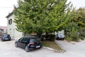 Ein Auto parkt neben einem Baum vor einem Haus in der Unterkunft Wild in Sinj
