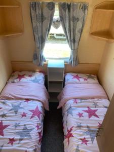 twee bedden in een kleine kamer met een raam bij Glade 34 in Bideford
