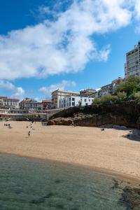 a beach with people on the sand and buildings at Hôtel de La Plage in Biarritz