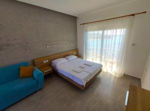 ein Schlafzimmer mit einem Bett und einem blauen Sofa in der Unterkunft OASİS AT AYFİLON in Rizokarpaso