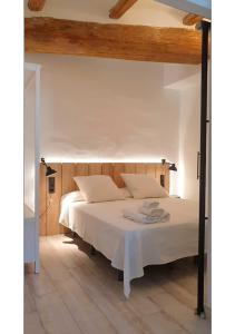 サン・ホアン・デ・レ・アバデセスにあるCasa Filomena apartamento de diseño en St. Joan de les Abadessesの白いベッド1台(木製ヘッドボード付)が備わるベッドルーム1室が備わります。