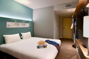 a hotel room with a bed with a hat on it at ibis budget Saint Nazaire Centre Gare in Saint-Nazaire