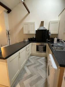 a kitchen with white cabinets and a black counter top at Flat 2 Chestergate in Macclesfield