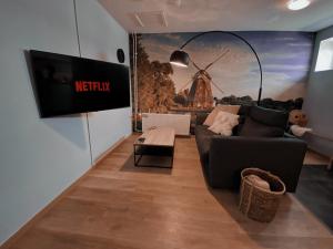 a living room with a couch and a tv on a wall at Loods 123 bed & kitchen in Landgraaf