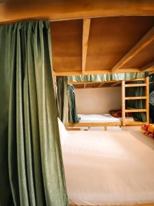 a bunk bed with green curtains in a room at Jungle by sturmfrei Manali in Manāli