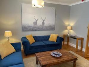 a living room with a blue couch and two deer paintings at Elmbank Stay - Drymen in Drymen