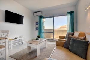 een woonkamer met een bank en een groot raam bij 095 - Bright & Comfortable Holiday Apartment With Water Park & Sea Views in Benalmádena