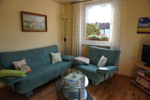 ein Wohnzimmer mit einem blauen Sofa und 2 Stühlen in der Unterkunft Ferienwohnung Familie Frank in Kurort Rathen