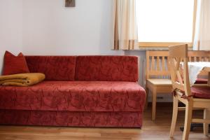a red couch in a living room with a table at Hilber App Furchetta in Villnoss +25 photos