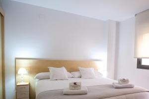 una camera da letto con un grande letto bianco con due asciugamani di El Portal de María ad Aínsa