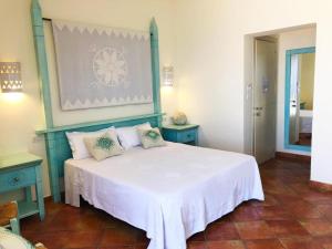 Schlafzimmer mit einem großen weißen Bett und blauen Möbeln in der Unterkunft LH Pedraladda Resort in Castelsardo