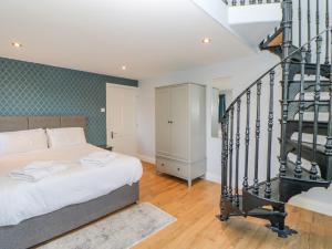 a bedroom with a bed and a spiral staircase at Burns Cottage in Barnard Castle