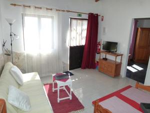 a living room with a white couch and a tv at Casa do Gerd in Aljezur