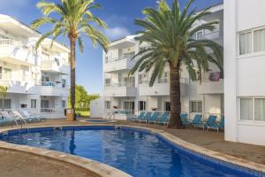 una piscina frente a un edificio con palmeras en Palm Garden en Port d'Alcudia