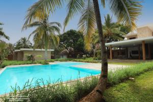 a swimming pool in front of a house with palm trees at Anki Lodge in Nosy Be