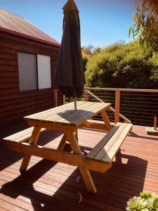 a wooden picnic table with an umbrella and a picnic at Red ceder cottage - Great ocean road - Port Campbell in Port Campbell