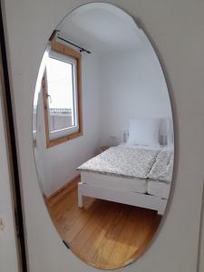 a mirror in a bedroom with a bed and a window at LAND-Häusle in Weikersheim