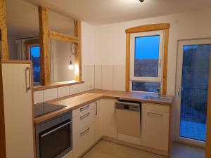 a kitchen with white cabinets and a sink and two windows at LAND-Häusle in Weikersheim