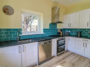 a kitchen with white cabinets and blue tiles at North Lodge in Appleby