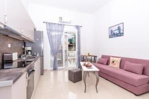 Eliora Studio & Aelia Apartment في مدينة هيراكيلون: غرفة معيشة مع أريكة أرجوانية وطاولة
