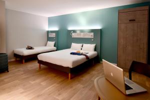 a room with two beds and a laptop on a desk at ibis budget Saint Nazaire Centre Gare in Saint-Nazaire