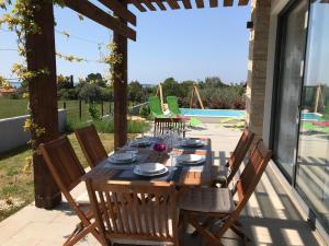 a wooden table and chairs on a patio at Villa Rosa dei Venti - Peroj - Amazing sea view in Peroj