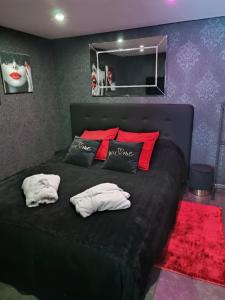 Schlafzimmer mit einem schwarzen Bett und roten Kissen in der Unterkunft AVEC TOI suite spa in Barlin