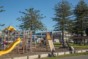 a park with a playground with slides and people at Navigate Seaside Hotel in Napier