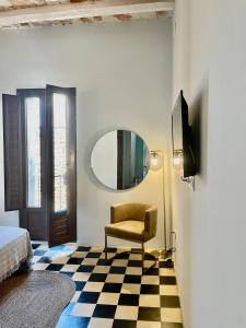 Schlafzimmer mit Spiegel, Stuhl und Schachbrettboden in der Unterkunft La Casa del Carrer Major in Santa Magdalena de Pulpis