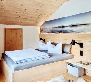 1 dormitorio con 1 cama y pared de madera en Ferienwohnung ChiemseeAlpenBlick, en Breitbrunn am Chiemsee