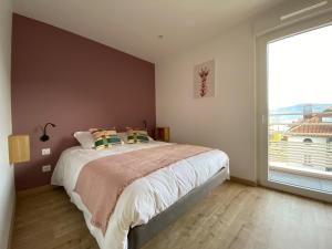 een slaapkamer met een groot bed en een groot raam bij L'Escampette, superbe appartement avec terrasse in Gérardmer