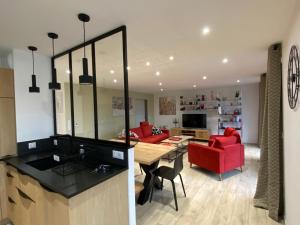 een keuken en een woonkamer met rode stoelen en een tafel bij L'Escampette, superbe appartement avec terrasse in Gérardmer