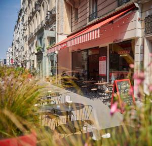 an outdoor cafe with tables and chairs on a city street at Normandy Le Chantier in Paris