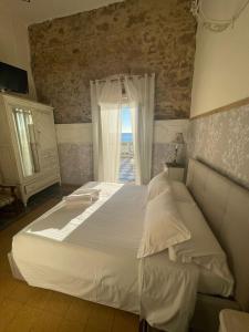 a bedroom with a large white bed with a window at Locanda Garzelli in Quercianella