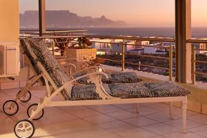 a bench on a balcony with a view of the ocean at Seaside Village Penthouse F23 by HostAgents in Cape Town