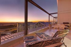 a balcony with a table and chairs and a sunset at Seaside Village Penthouse F23 by HostAgents in Cape Town