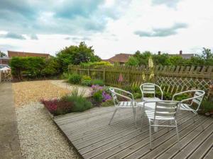 a wooden deck with two chairs and a table at Pebble Cottage in Saltburn-by-the-Sea